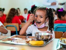 Niña comiendo su merienda escolar preparada en la escuela en Venezuela.
